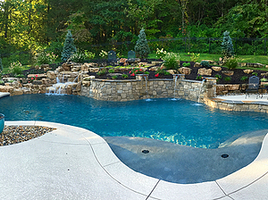 st. louis custom designed freeform concrete pool with raised wall, scuppers, boulder water feature and tan shelf