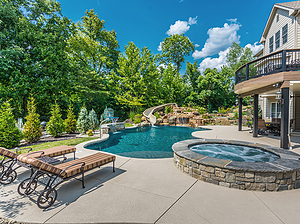 st. louis custom designed freeform concrete pool, raised concrete spa, boulder water feature with fiberglass slide, raised wall with sheer descent, lounge chairs, basketball