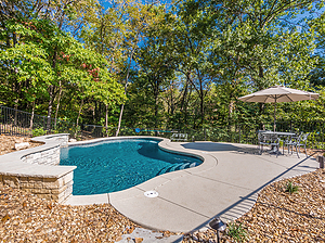 st. louis custom designed freeform concrete pool with cantilever coping and raised stone wall with flagstone coping and stone veneer, gravel planting beds