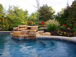 St. Louis custom designed freeform concrete pool with textured cantilever coping and boulder water feature surrounded by colorful landscaping