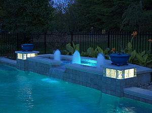 St. Louis custom designed geometric concrete pool with cantilever coping and water feature with geyser fountains, spillover feature and fiber optic lighting at night