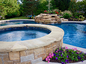 st. louis custom designed freeform pool, raised concrete spa with stone veneer and flagstone cap