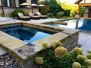 st. louis custom designed geometric concrete pool, stand alone concrete spa with exposed walls with stone veneer and flagstone cap