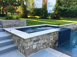 st. louis custom designed concrete pool, raised concrete spa with stone veneer, tile spillover and pewter mist cut stone coping