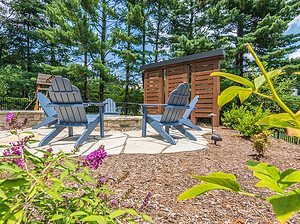 Flagstone patio with blue chairs, round fire pit and custom wooden privacy panels