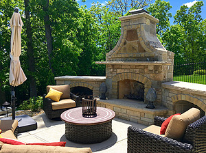 Concrete patio with stone fireplace and brown and beige patio furniture