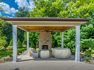 Covered concrete patio with stone fireplace, covered furniture and ceiling fan