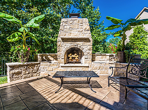 Travertine patio with black metal furniture and stone fireplace