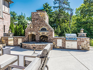 Concrete patio with beige furniture, brick fireplace and outdoor kitchen