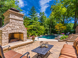 Brick paver patio with stone fireplace, black metal patio furniture with tan cushions