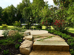 Ledge rock steps and flagstone path leading to concrete patio with seating area