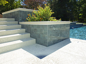 Textured concrete steps next to large planted beds and St. Louis custom designed concrete pool