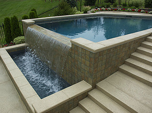 Textured concrete steps leading up to St. Louis custom geometric concrete pool with exposed tiled walls and vanishing edge