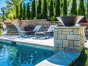 Shawnee ledgerock steps leading down to St. Louis custom designed geometric concrete pool with stone column, fire bowl and lounge chairs