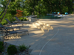 Textured concrete steps leading from lounge chair area up to St. Louis custom designed freeform concrete pool