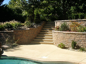 Textured concrete steps surrounded on both sides by landscaped retaining walls