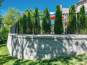 Modular block retaining wall with landscaping and black fence