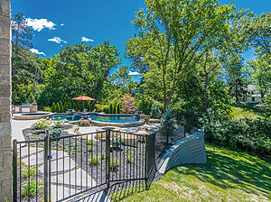 St. Louis custom designed freeform concrete pool with black fence and modular block retaining wall