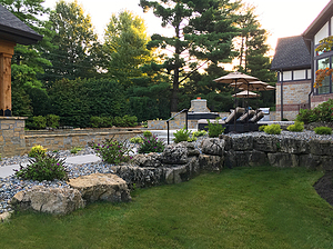 Boulder retaining wall running alongside landscaped gravel planting beds