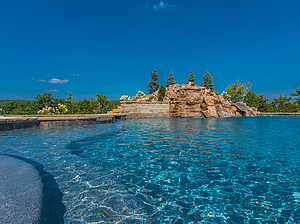 st. louis custom designed freeform concrete pool with boulder water feature and tan shelf