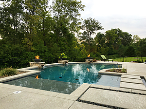 st. louis custom designed concrete pool, tan shelf, floating steps, stone columns with fire bowls and scuppers