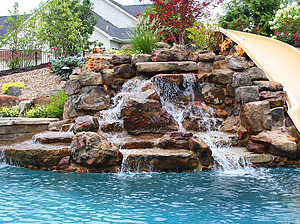 St. Louis custom designed concrete pool with boulder water feature with slide and inset fire features