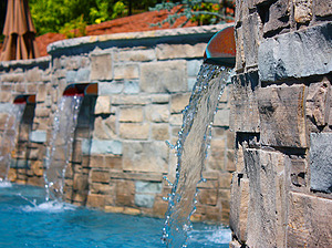 St. Louis custom designed freeform concrete pool with raised wall with stone veneer, flagstone coping and three copper scuppers