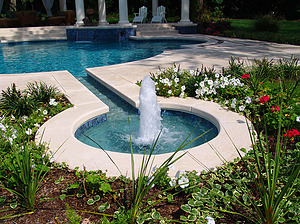 St. Louis custom designed Grecian concrete pool with keyhole water feature with cascade fountain and surrounded by red and white flowers
