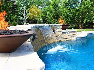 St. Louis custom designed freeform concrete pool with raised wall with stone veneer and flagstone coping, two medallions, two fire bowls and sheer descent
