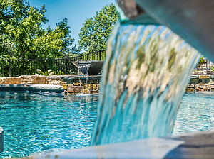 St. Louis custom designed freeform concrete pool with raised wall with stone veneer, flagstone coping and two water fire bowls