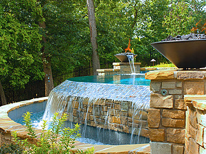 St. Louis custom designed freeform concrete pool with flagstone coping, tiled vanishing edge and two water fire bowls