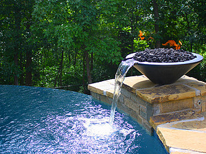 St. Louis custom designed freeform concrete pool with vanishing edge and stone column with waster fire bowl