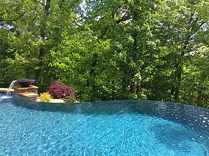 St. Louis custom designed freeform concrete pool with vanishing edge and stone column with water fire bowl
