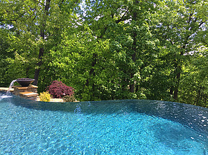 St. Louis custom designed freeform concrete pool with vanishing edge and stone column with water fire bowl