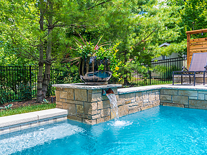St. Louis custom designed geometric concrete pool with cantilever coping and raised wall with stone veneer, flagstone coping and stone column with scupper and large planter
