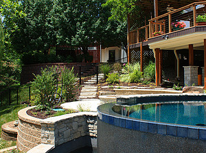Deck overlooking St. Louis custom designed freeform concrete pool with flagstone coping and vanishing edge water feature with blue tile and exposed wall