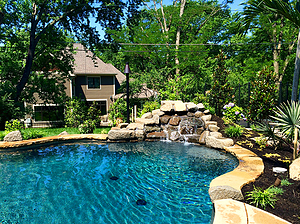 St. Louis custom designed freeform concrete pool with flagstone coping, boulder water feature, tiki torch and Hawaiin inspired landscaping