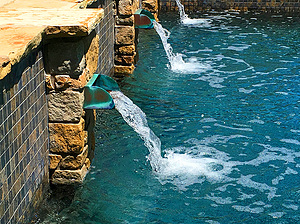 St. Louis custom designed geometric concrete pool with flagstone coping, tiled raised wall and stone columns with copper scuppers