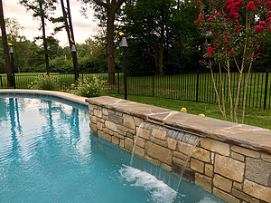St. Louis custom designed concrete pool with raised wall with stone veneer, flagstone coping and sheer descent water feature