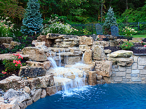 Landscaped St. Louis custom designed freeform concrete pool with boulder water feature and raised wall with stone veneer