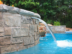 St. Louis custom designed freeform concrete pool with raised spa with stone veneer, flagstone coping and sheer descent water feature