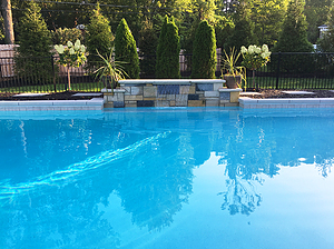 St. Louis custom designed geometric concrete pool with cantilever coping and raised wall with stone veneer and sheer descent water feature