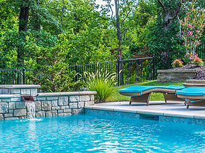 St. Louis custom designed geometric concrete pool with raised wall with stone veneer and copper scupper and teal lounge chairs