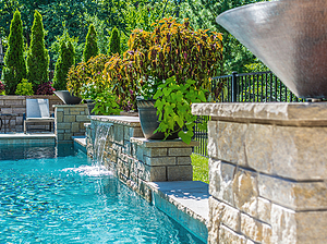 St. Louis custom designed geometric concrete pool with flagstone coping, raised wall with stone veneer, sheer descent and fire bowls
