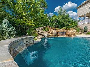 St. Louis custom designed freeform concrete pool with large boulder water feature with slide and raised wall with stone veneer, flagstone coping and sheer descent