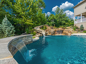 St. Louis custom designed freeform concrete pool with large boulder water feature with slide and raised wall with stone veneer, flagstone coping and sheer descent