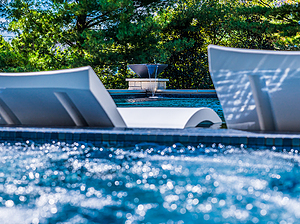 Ledge loungers in St. Louis custom designed geometric pool with stone column with water fire bowl