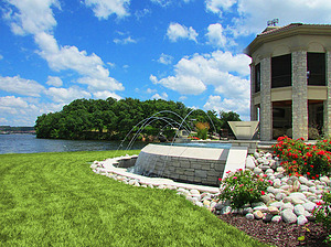 st. louis custom designed concrete pool with stone veneer on exposed wall, vanishing edge and laminar jets overlooking lake