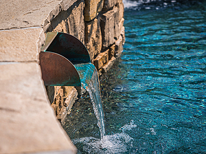 St. Louis custom designed concrete pool with raised wall with stone veneer, flagstone coping and copper scupper