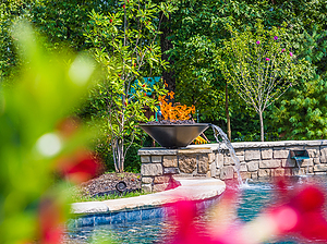 St. Louis custom designed freeform concrete pool with raised wall with stone veneer, flagstone coping, fire water bowl and scupper